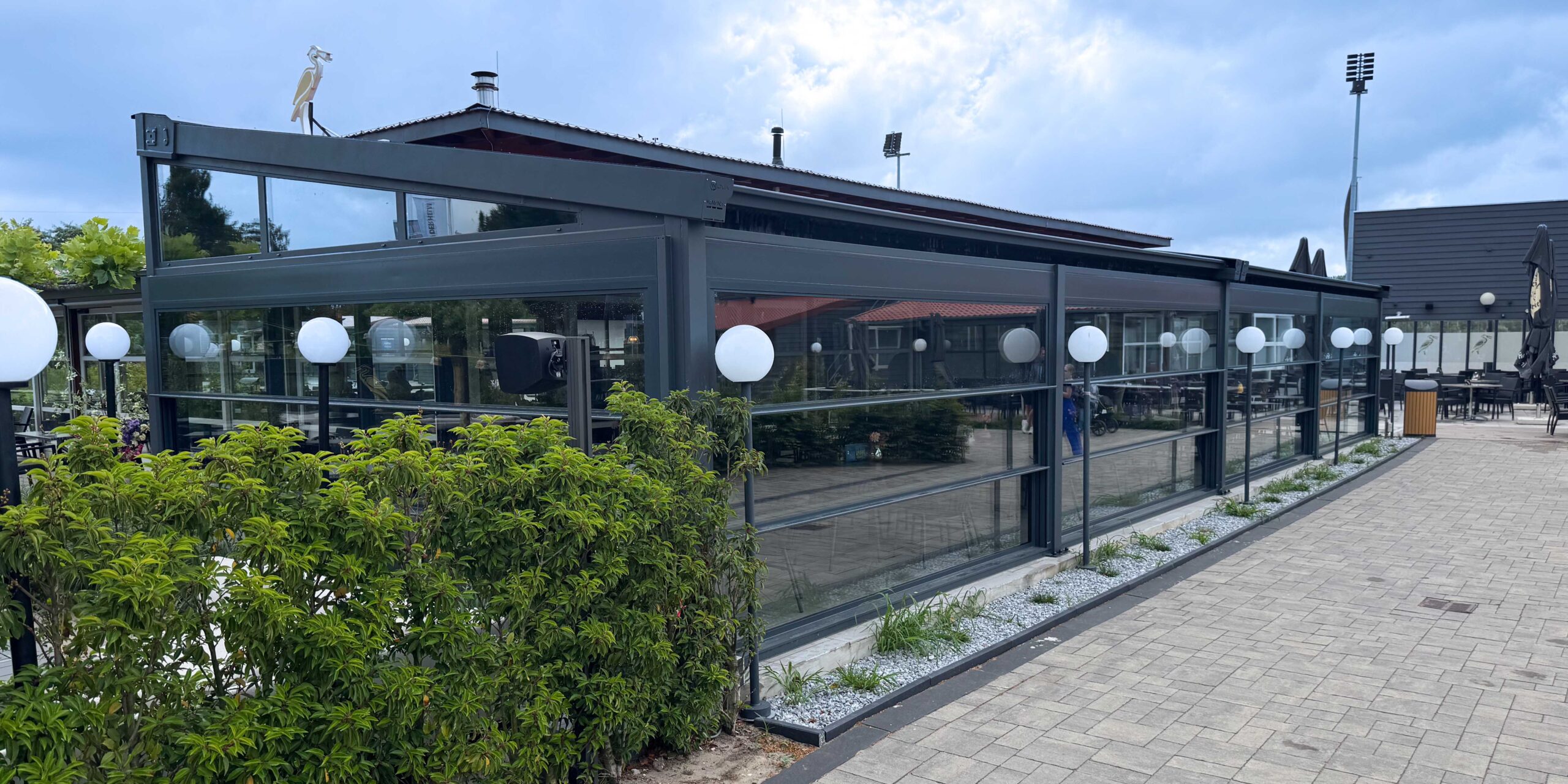 Horeca terrasoverkapping met glazen wanden en aluminium constructie bij Golfbaan Delfland