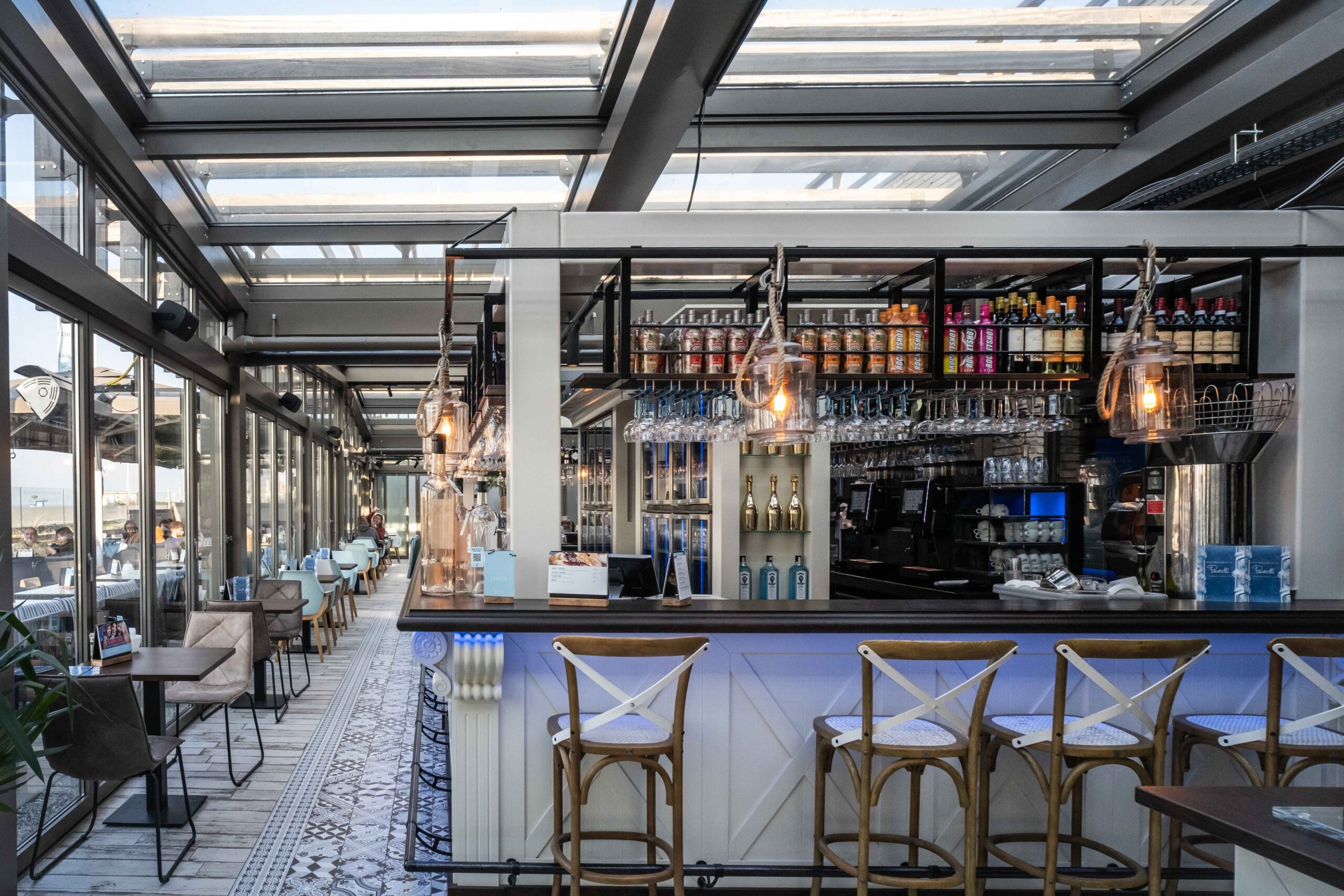 Horeca interieur onder glazen schuifdak met bar en zitplaatsen in Nieuw Kijkduin
