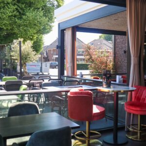 Verticale schuiframen geopend in horeca serre voor open terrasbeleving